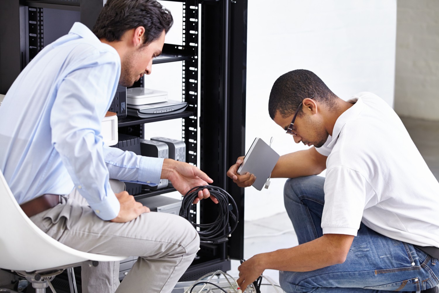 Dos técnicos trabajan en un armario de servidores de una oficina