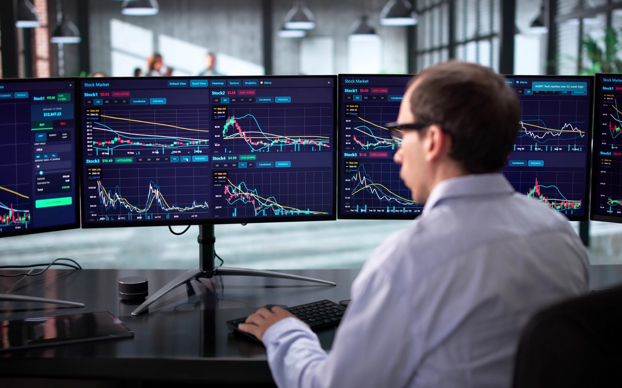 Profesional ante varias pantallas con datos de mercados financieros