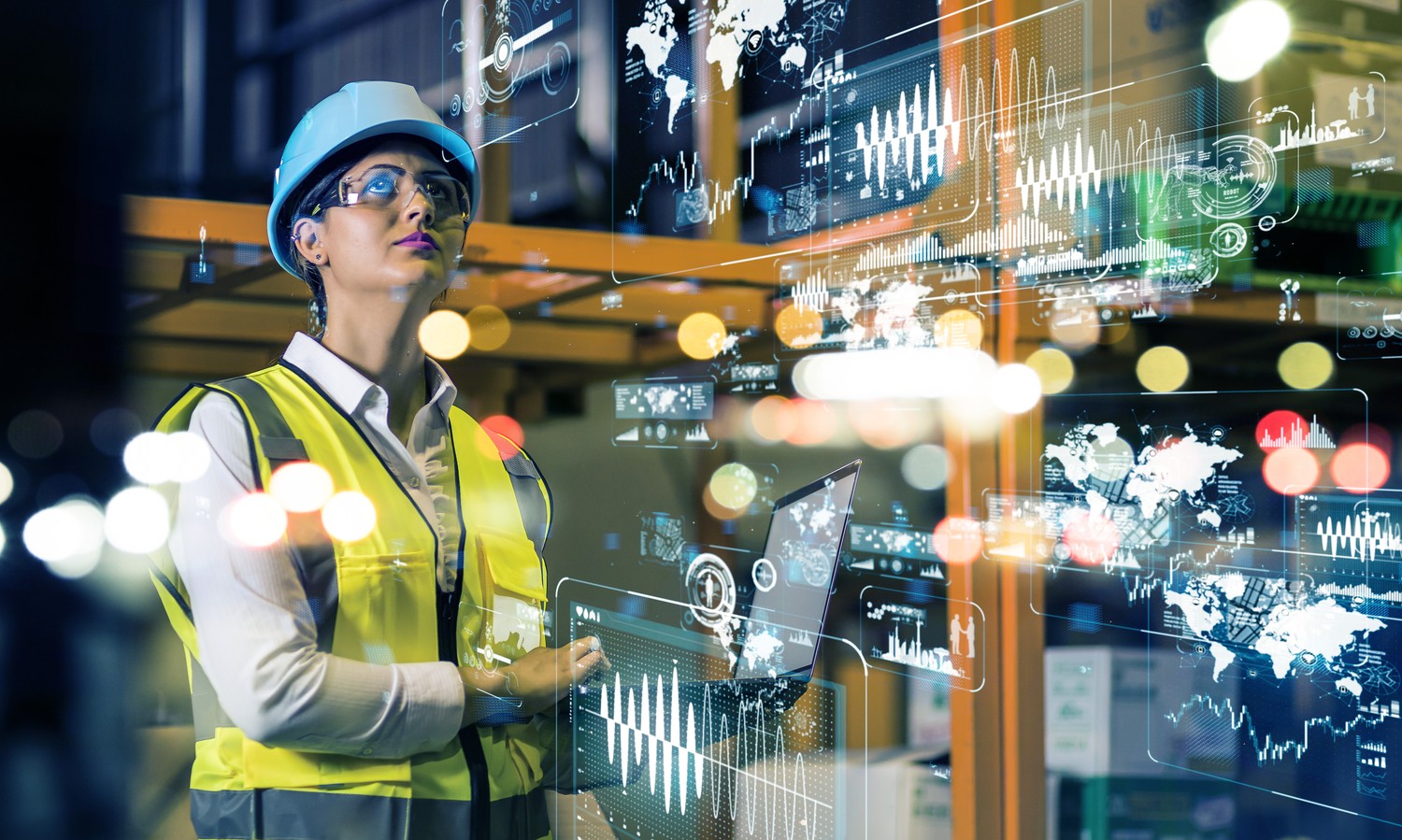 Ingeniera con casco y chaleco ante paneles de datos en una planta industrial