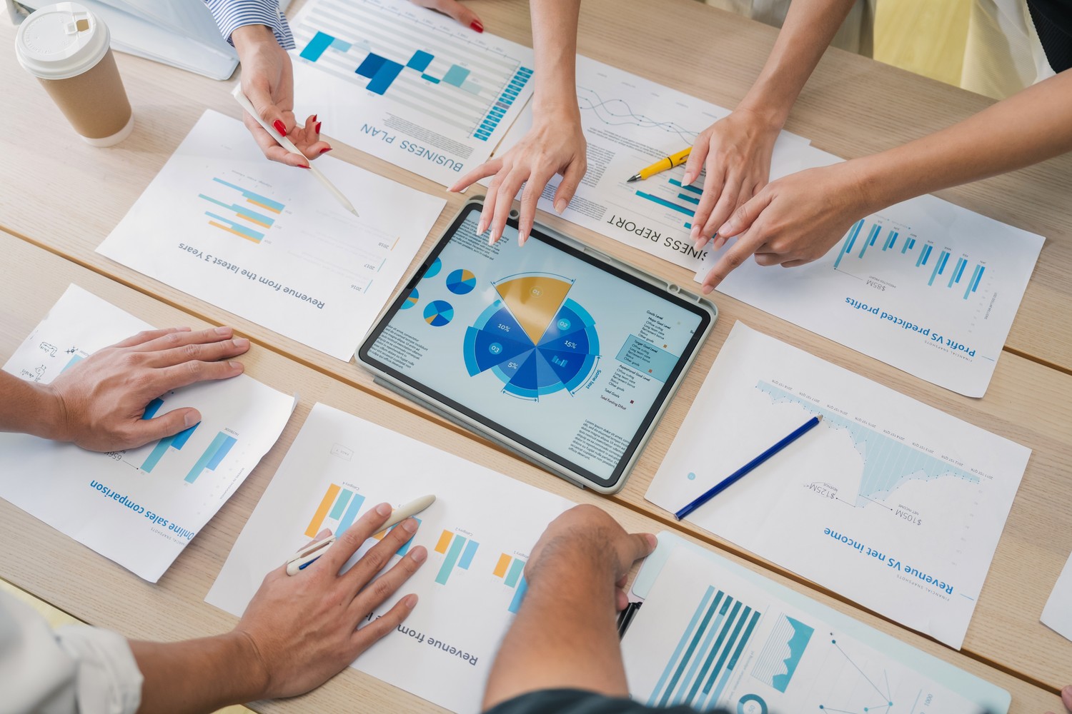 Vista cenital de manos analizando gráficos y un panel en una tableta