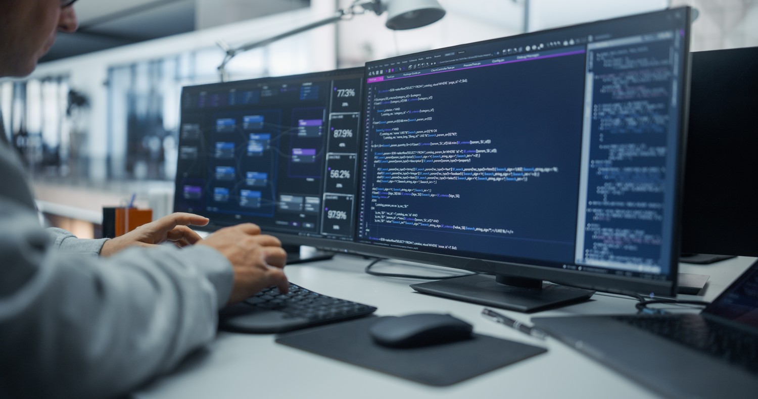 Programador trabajando con código en varios monitores
