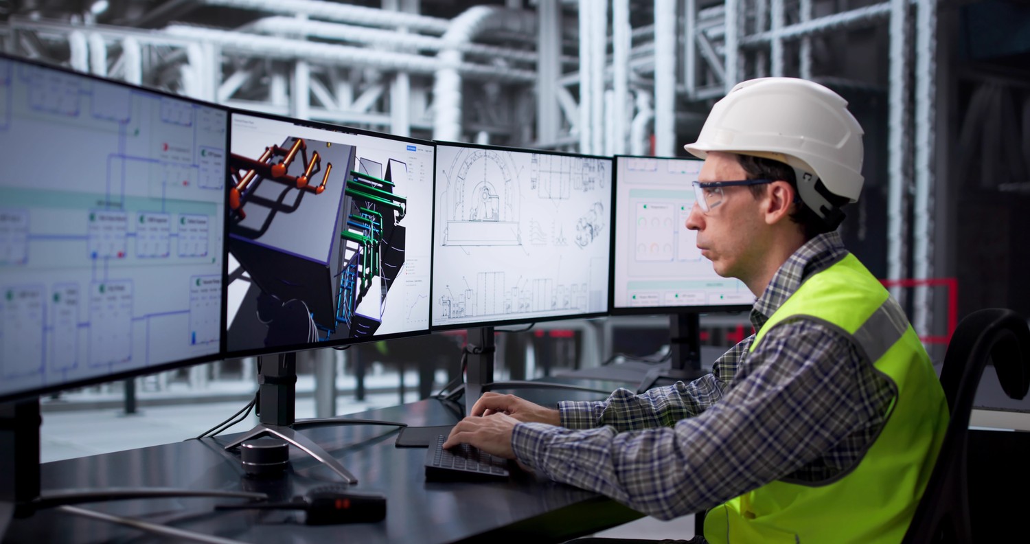Ingeniero con casco revisando el diseño 3D de tuberías en varios monitores