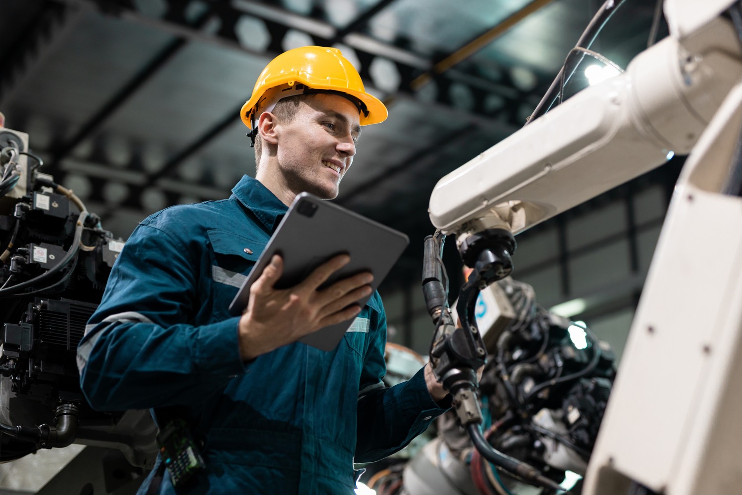 Técnico con tableta junto a un brazo robótico en una nave industrial
