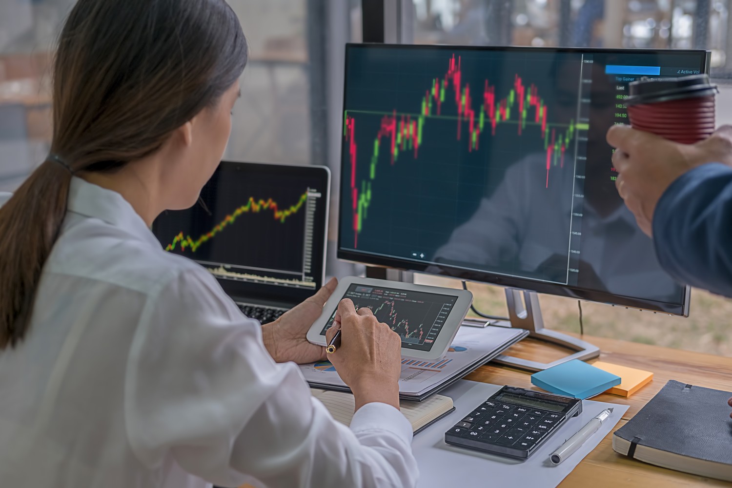 Profesional analizando gráficos de mercados financieros en varias pantallas