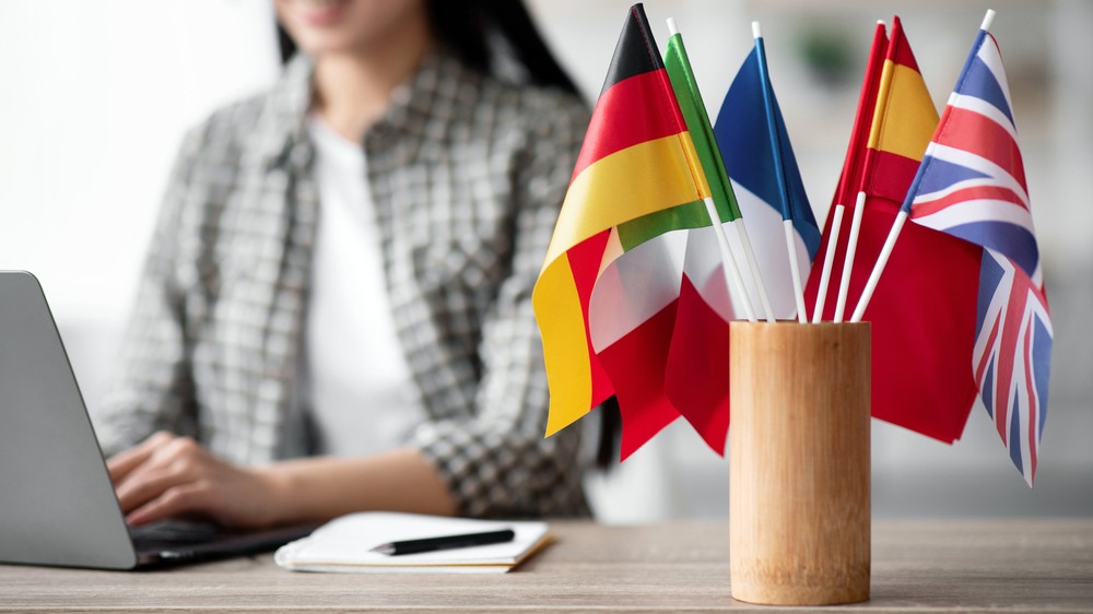 Banderas de varios países junto a una persona trabajando con el portátil